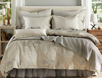 Zoya Ash duvet cover shown on bed with coordinating bedding. There are sidetables on either side with windows above them.