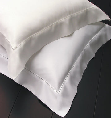 White and Ivory shams stacked on top of each other with hemstitched flanges