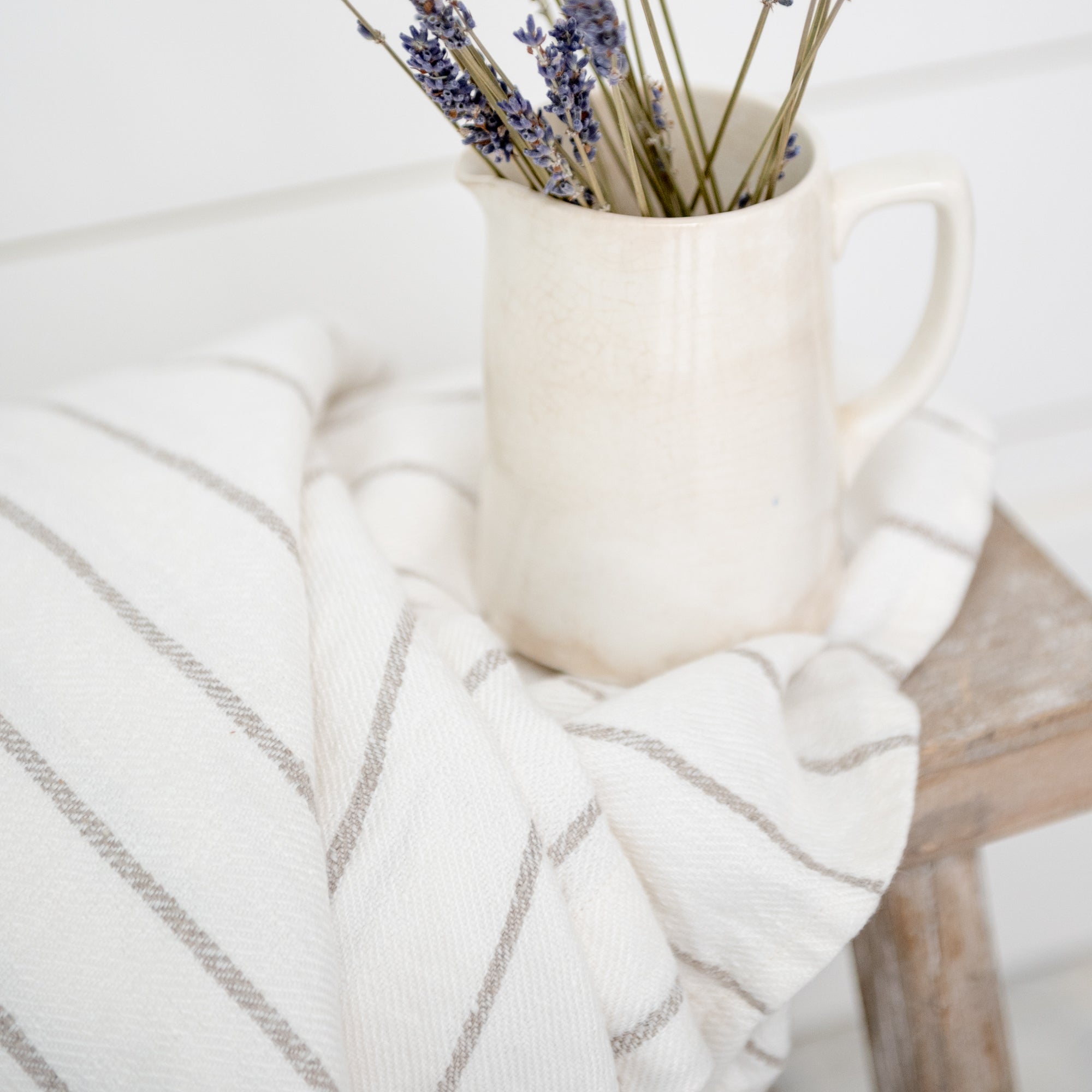 Striped Forte Towel shown on bench under white ceramic pot with lavender stems in.