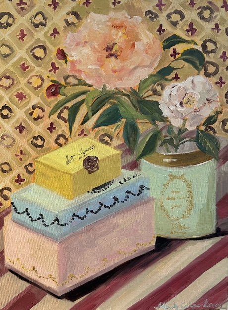 Decorative pink, blue and yellow chocolate boxes stacked next to Laduree canister with peonies in.