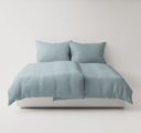 Light blue textured bedding set up on a bed