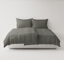 Gray textured bedding set on a white bed frame against a white background