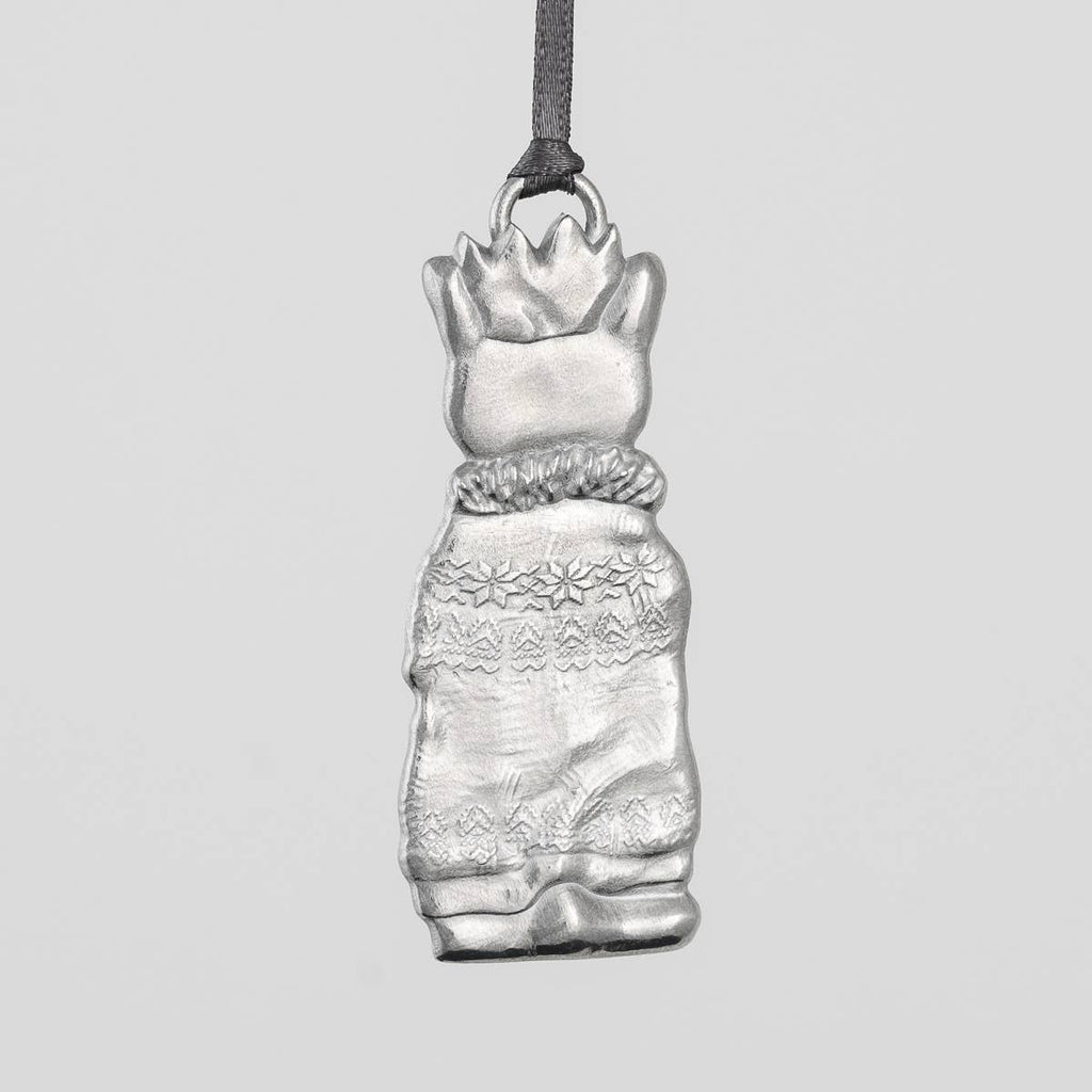 Pewter cat-shaped ornament with a crown, scarf and sweater on a gray background