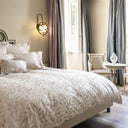 Bed with leafy patterned bedding in a well-lit bedroom.
