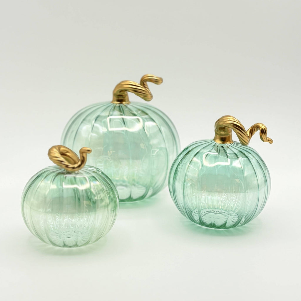 Three green glass pumpkins with gold stems on a white background