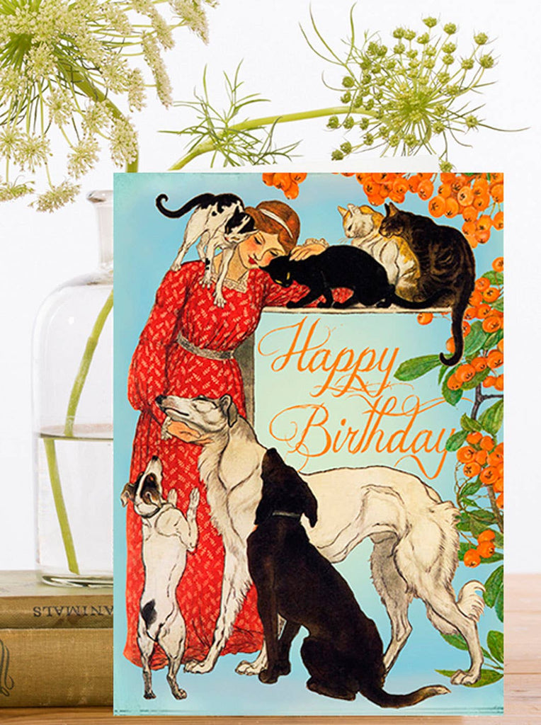 Vintage-style birthday card with a woman in a red dress surrounded by cats and dogs, featuring the text 'Happy Birthday'.