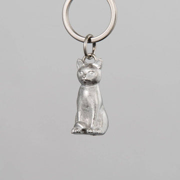 Pewter cat-shaped keychain on a gray background