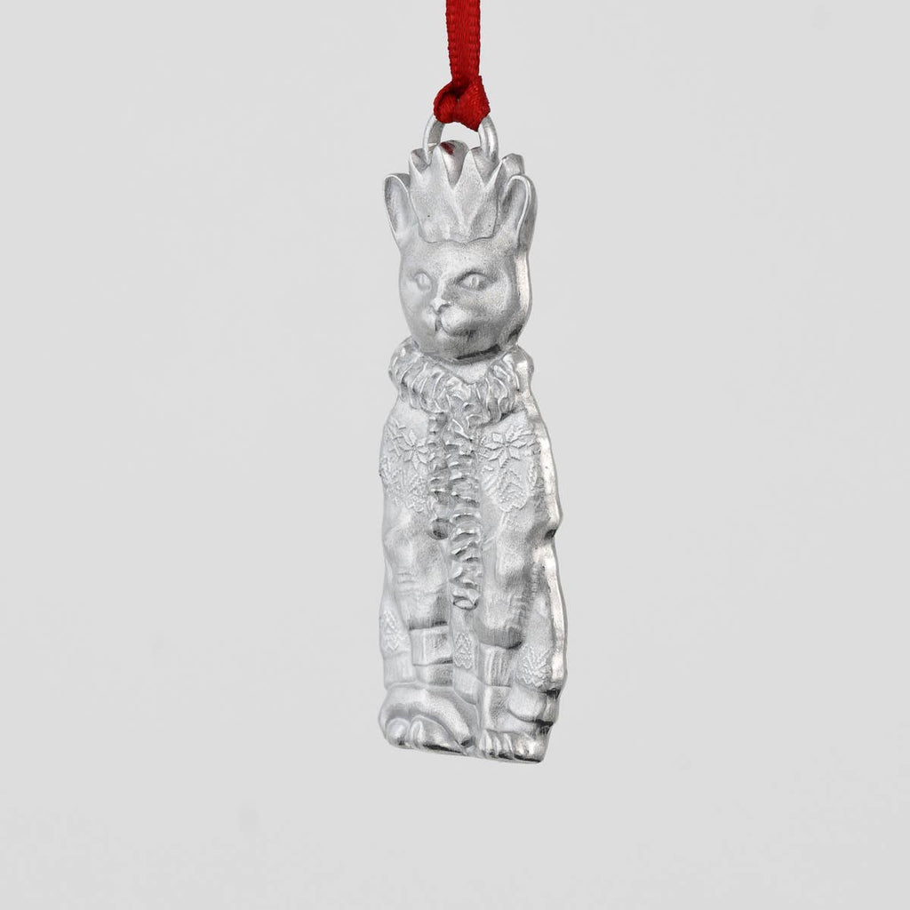 Pewter cat-shaped ornament with a crown, scarf and sweater on a gray background