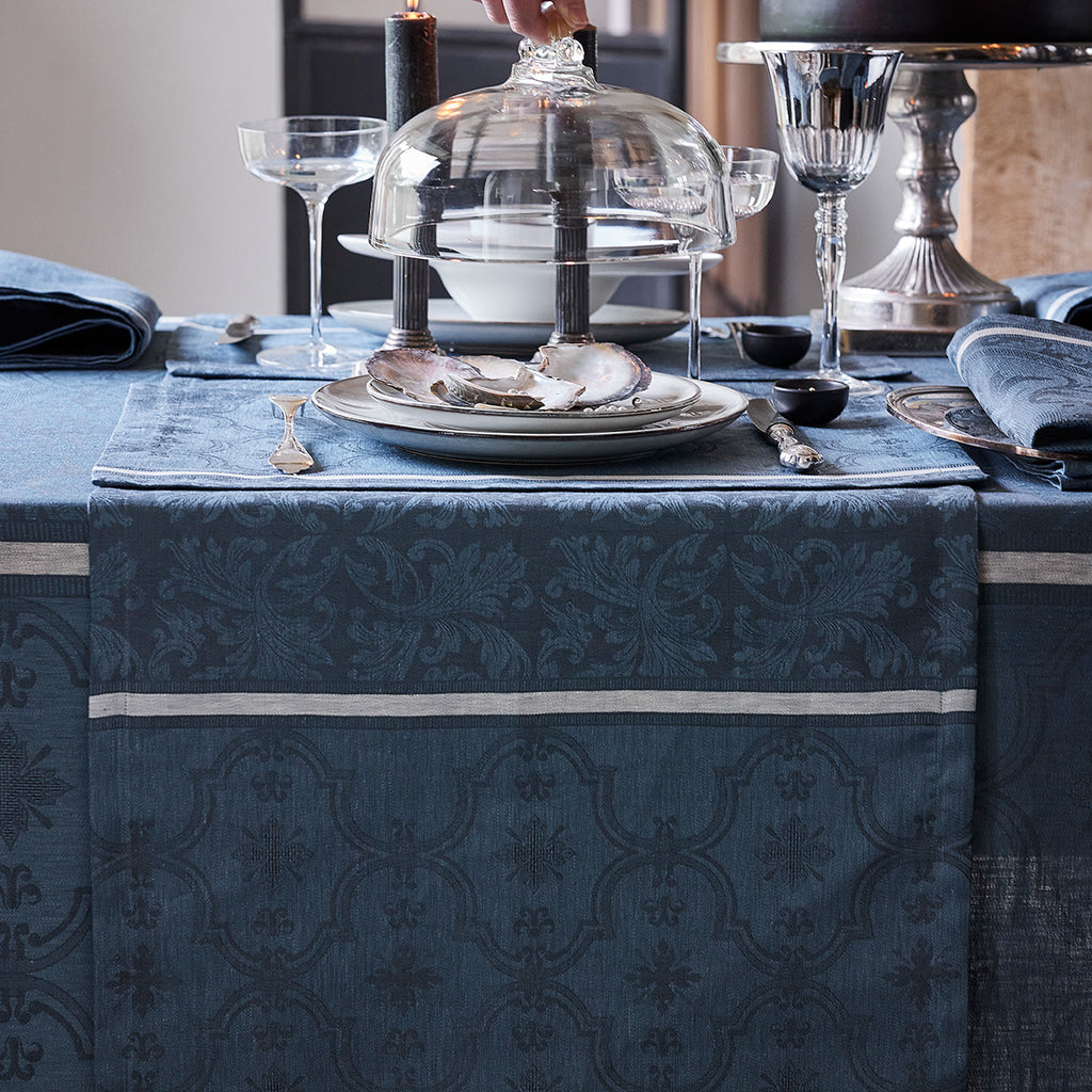 Armoiries Blue Runner shown on table with place setting and glass cover being lowered over plate.