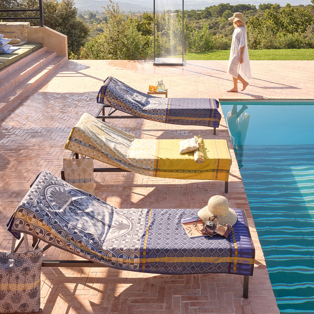 Palmeraie beach towels by the poolside on pool lounger chairs.