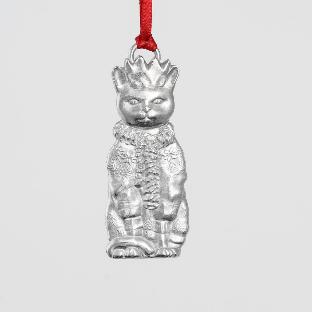 Pewter cat-shaped ornament with a crown, scarf and sweater on a gray background