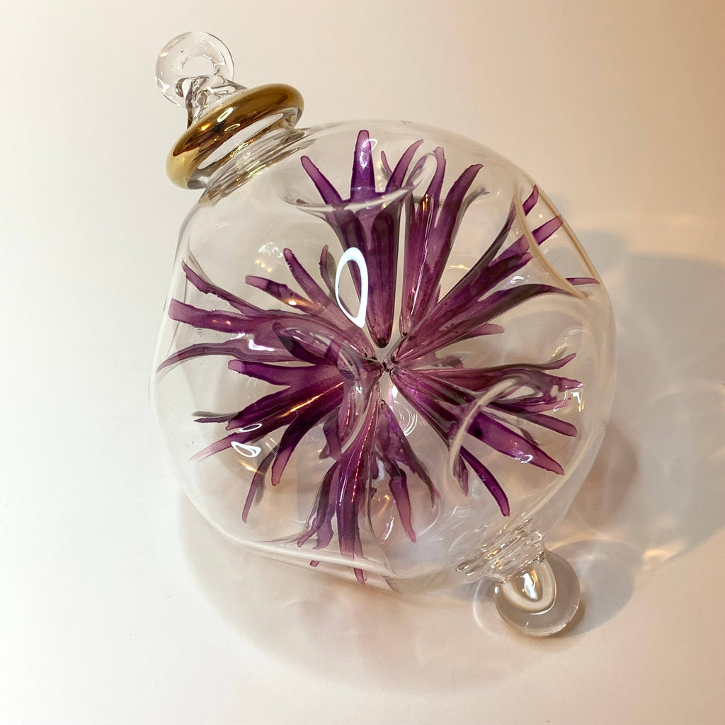 Glass ornament with a purple floral design 