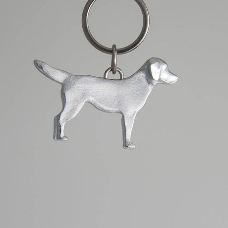Pewter dog-shaped keychain on a gray background