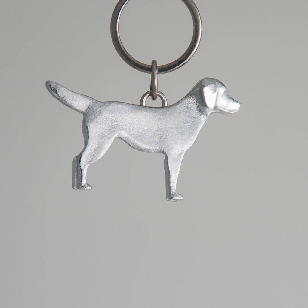 Pewter dog-shaped keychain on a gray background