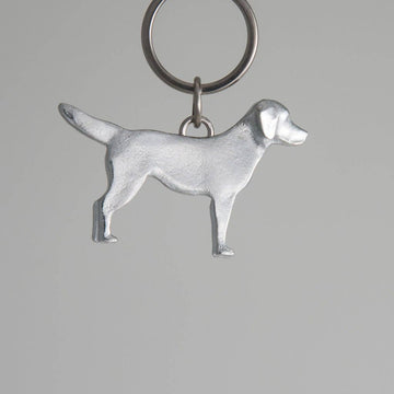 Pewter dog-shaped keychain on a gray background