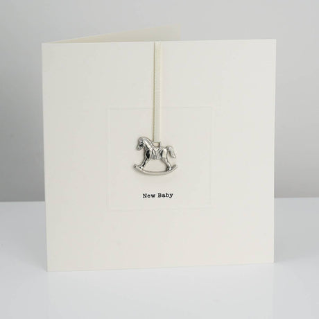 A greeting card with a detachable cast pewter keepsake, featuring a horse design and the text 'NEW BABY'.