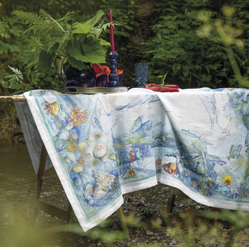 Isuela tablecloth with an ocean design in garden draped loosely on table. 