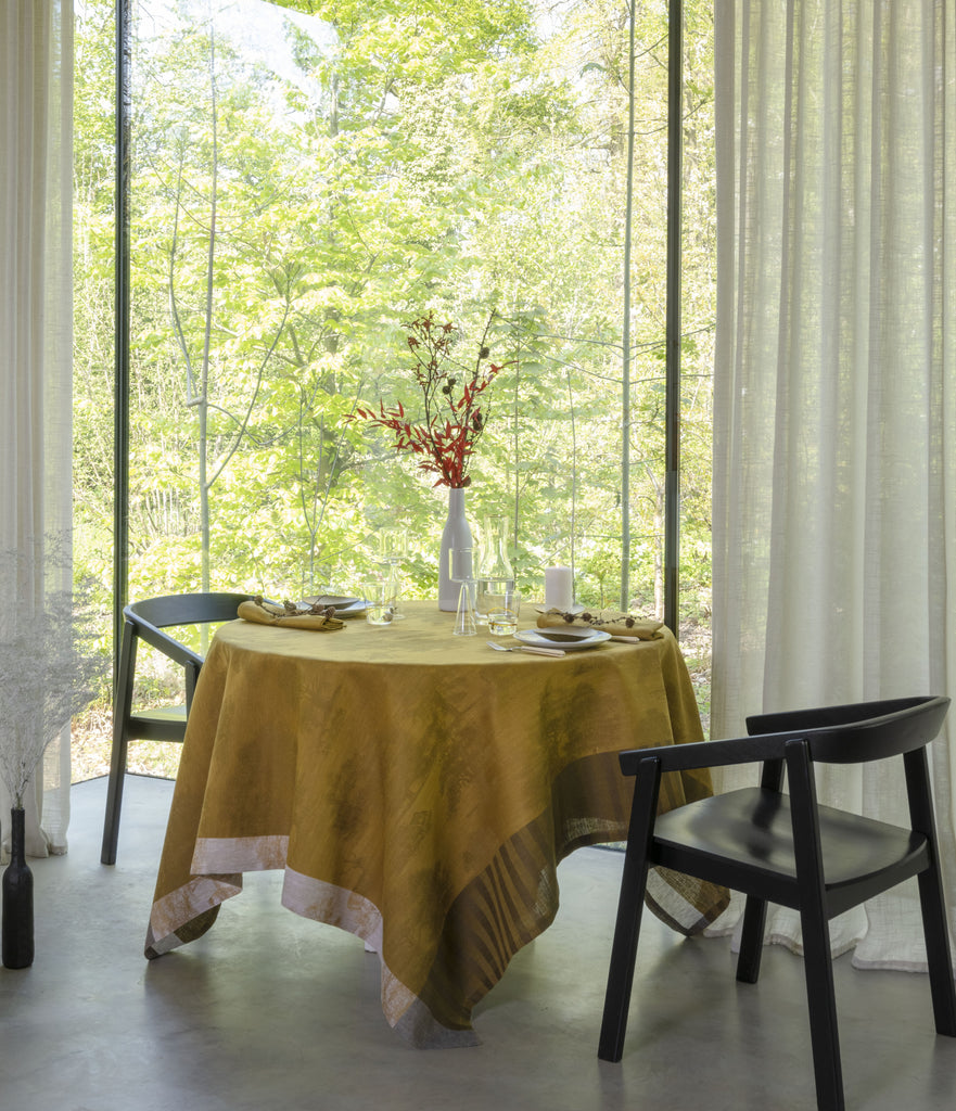 Souveraine Gold Square tablecloth on a round table with table setting 