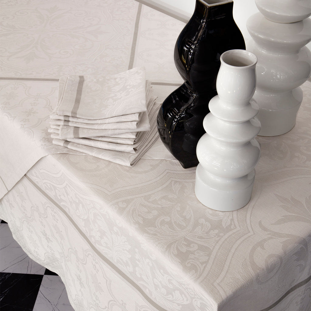 Armoiries Off White Tablecloth with napkins beside black and white vases 