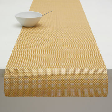 Basketweave gilded runner draped over edge of table with white bowl placed on it.