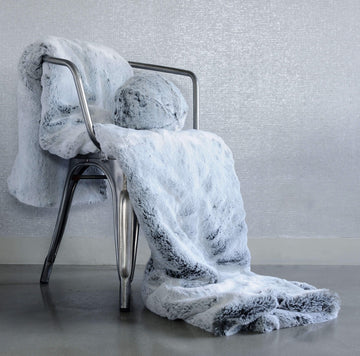 Glacier Faux Fur Throw draped on metal chair with Glacier Snowball resting on throw